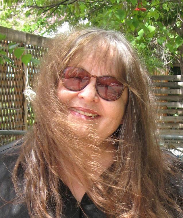 Picture of Michaelene Pendleton in the sunlight, wearing sunglasses, with her hair being blown in the wind.